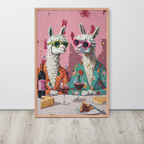 Funny kitchen wall art print featuring two stylized white alpacas wearing colorful sunglasses and suits, seated at a table with wine glasses, cheese, and cake against a pink background, displayed leaning against a white wall on a light wood floor.