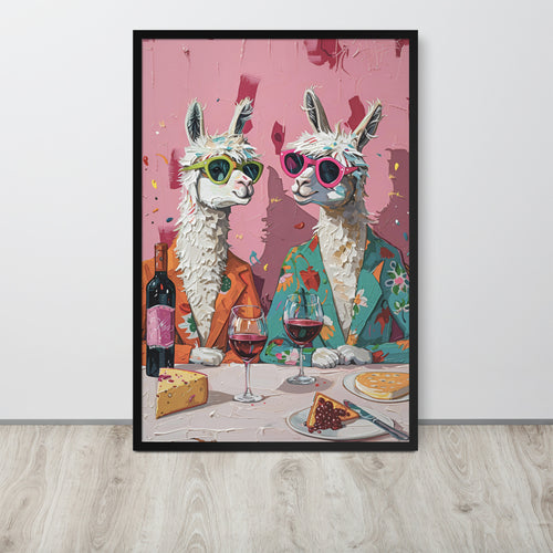 Funny alpaca art print featuring two stylized white alpacas wearing colorful sunglasses and suits, seated at a table with wine glasses, cheese, and cake against a pink background, displayed leaning against a white wall on a light wood floor.