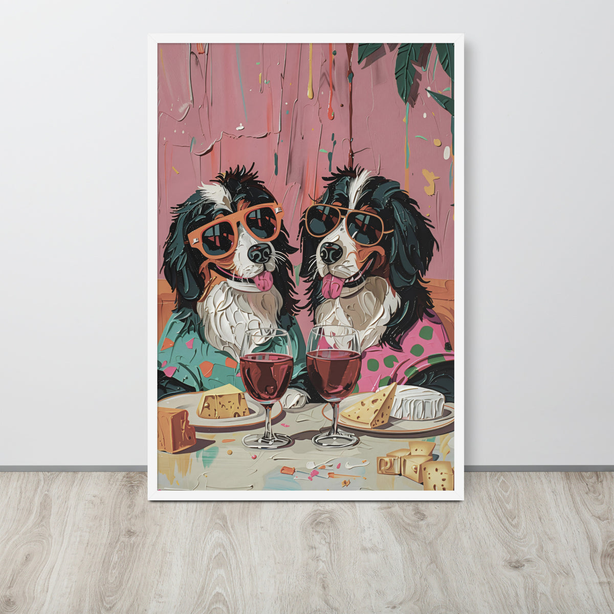 Dog dining room art print leaning against a light wall on a light wood floor. The print shows two Bernese mountain dogs wearing sunglasses and sitting at a table with wine glasses, cheese, and candy against a pink textured background.