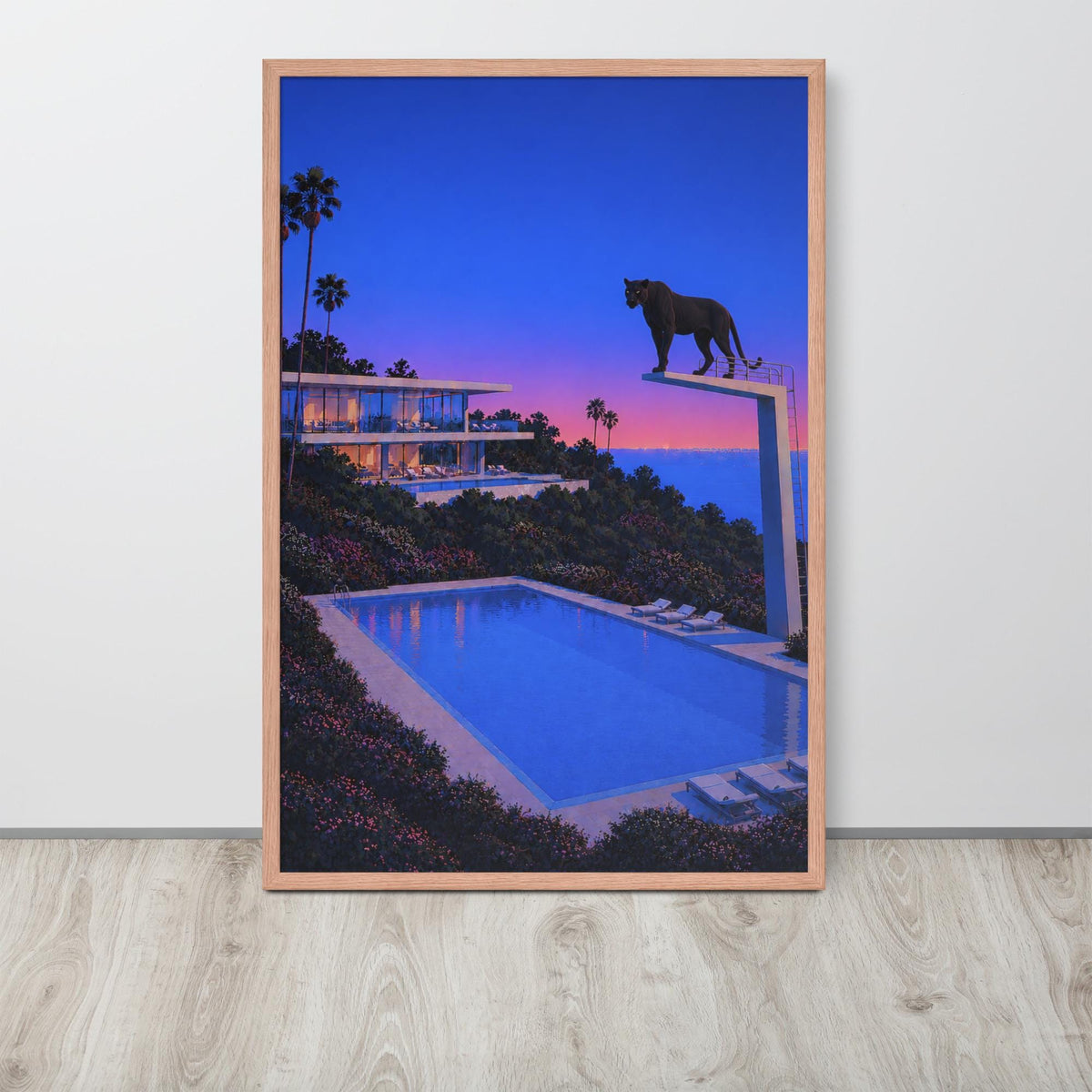 A framed abstract wall art print depicting a luxurious modern villa overlooking a swimming pool at twilight, with a silhouette of a big black panther cat standing on a diving board against a blue and pink sky. The print is shown leaning against a white wall on a light wood floor.