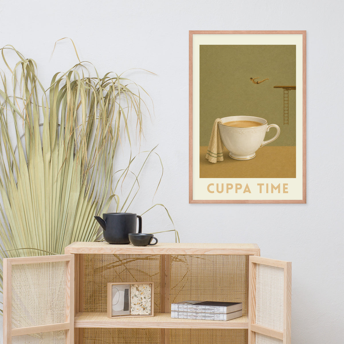 Vintage-style wall art print reading 'CUPPA TIME'. The print shows a white british teacup with a folded cream towel on an olive green background. A diver is mid-flight diving towards the cup.