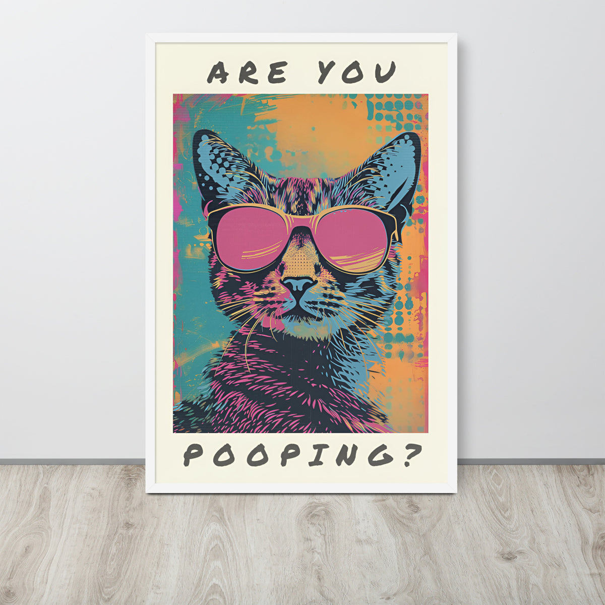 Funny cat washroom pop-art style poster leaning against a light wall on a wood floor. The poster shows a cat wearing pink sunglasses with the text 'ARE YOU POOPING?' in black at the top and bottom.