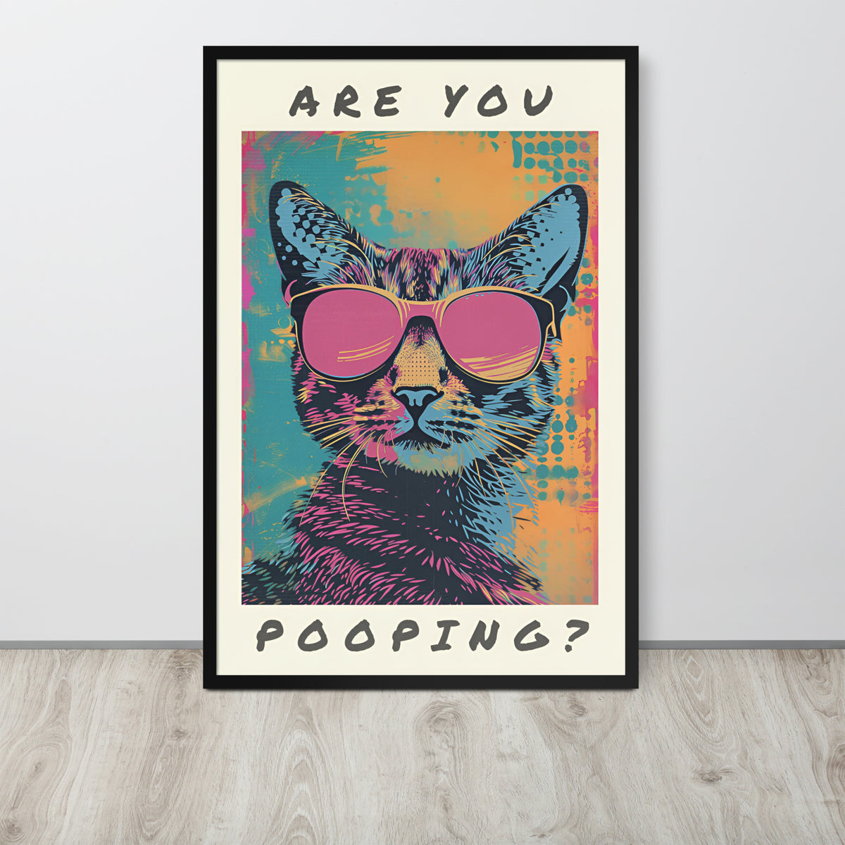 Funny cat bathroom pop-art style poster leaning against a light gray wall on a wood floor. The artwork shows a cat wearing pink sunglasses with the text 'ARE YOU POOPING?' in black lettering on a cream background.