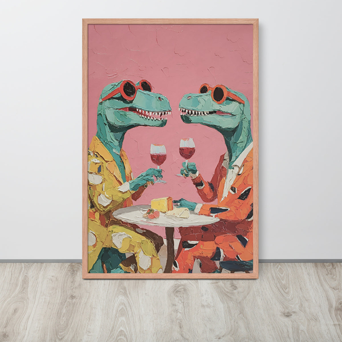 Dining room art print featuring two green t-rex dinosaur characters wearing sunglasses and holding wine glasses at a table, set against a pink background. The print is displayed leaning against a white wall on a light wood floor.
