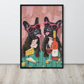 Funny kitchen art print featuring a whimsical illustration of two black French bulldogs wearing pink sunglasses, sitting at a teal table with cheese, wine, and a bottle. The print is displayed on a light wall above a light wood floor.
