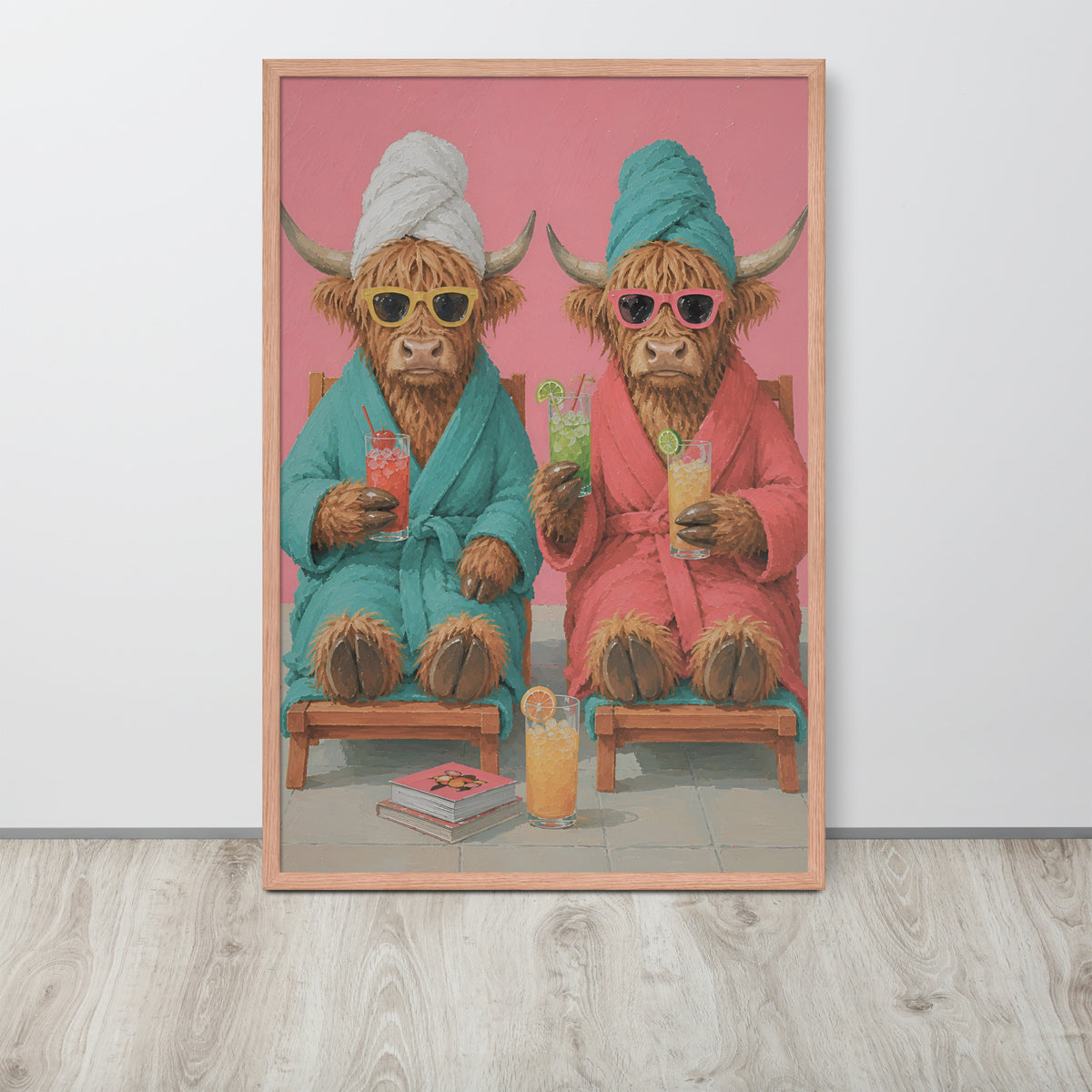 Funny spa room wall art print featuring a whimsical illustration of two Highland cows in colorful robes sitting on wooden chairs and holding cocktails, displayed against a light gray wall on a light wood floor.