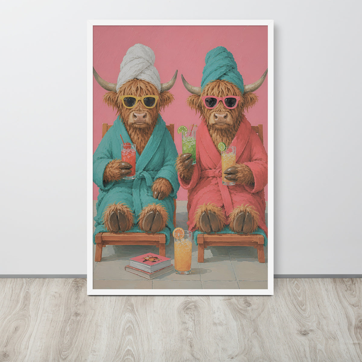 Funny bathroom toilet wall art print featuring two Highland cows in colorful bathrobes sitting on wooden chairs and holding cocktails, displayed against a light gray wall on a light wood floor.