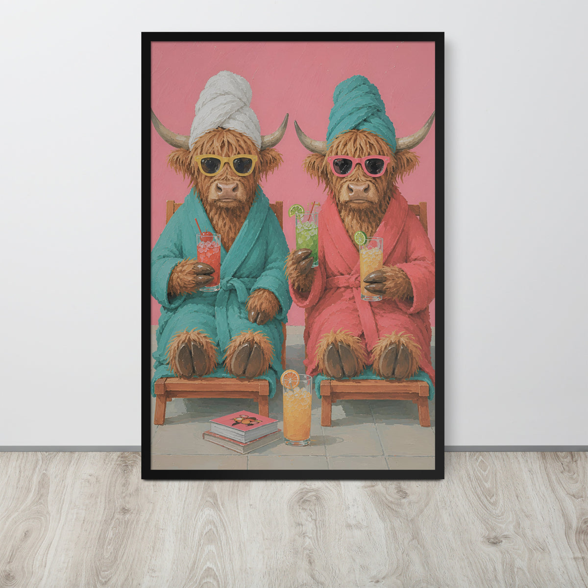 Funny bathroom wall art print featuring two Highland cows in colorful robes sitting on wooden chairs against a pink background, displayed on a light gray wall above a light wood floor.