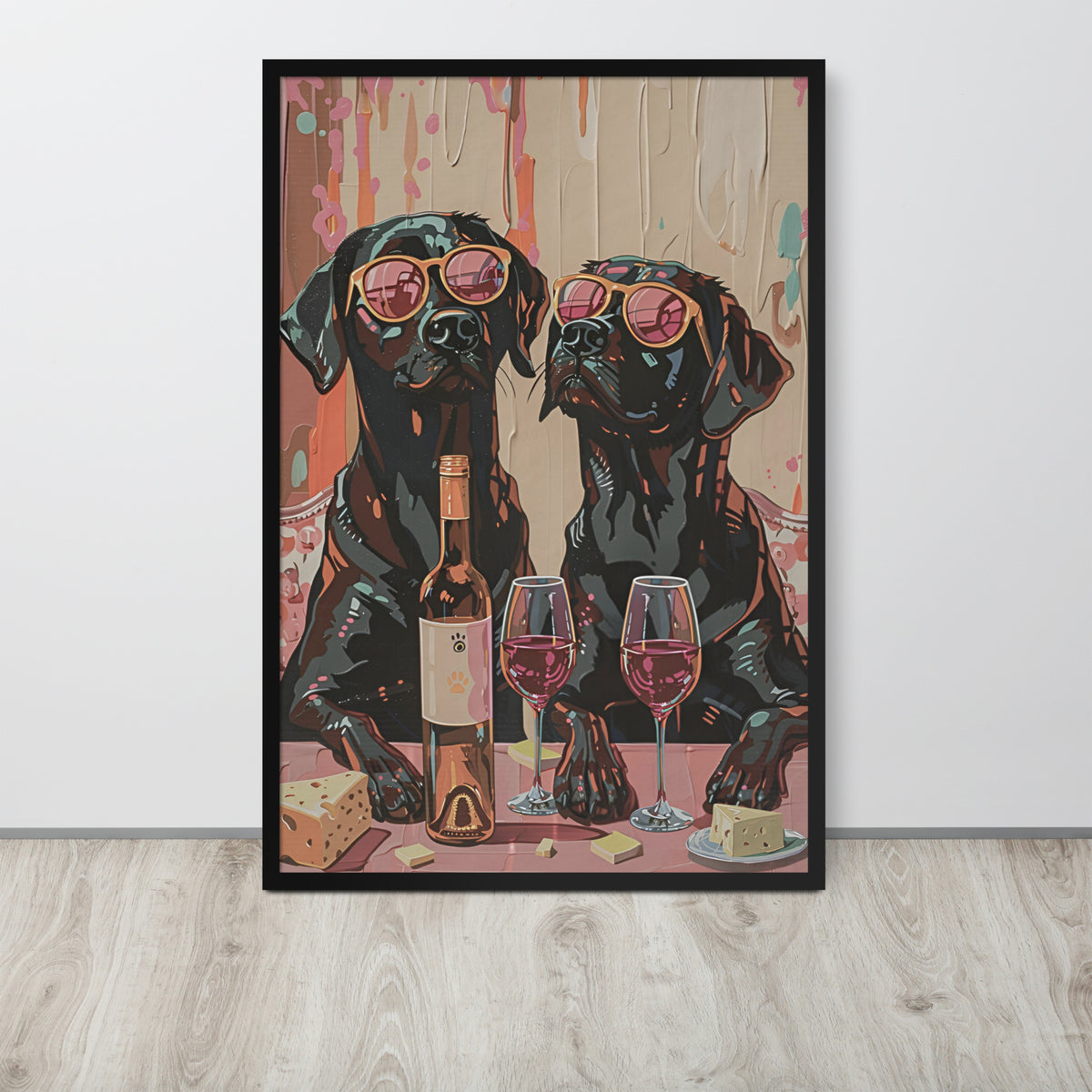 Funny labrador art print featuring a stylized illustration of two black labrador dogs wearing pink sunglasses at a table with wine glasses, a wine bottle, cheese, and a loaf, displayed against a light wall on a light wood floor.