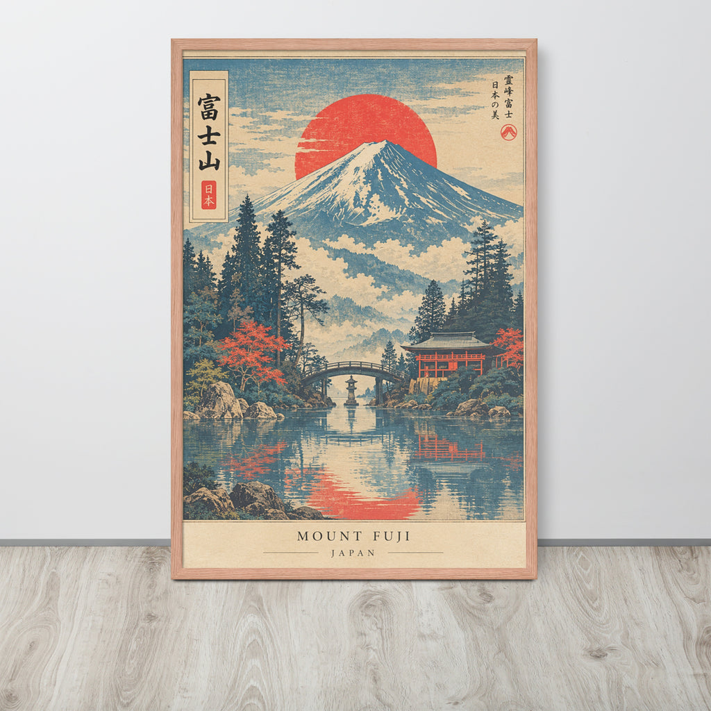 A framed Japanese-style art print of Mount Fuji with a large red sun, water reflection, trees, and a bridge, leaning against a light gray wall on a wood floor.