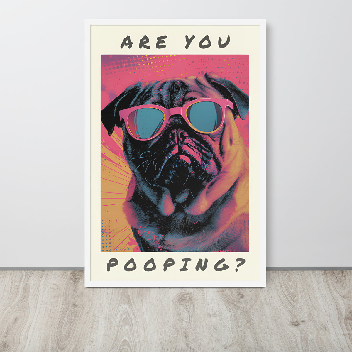 Funny toilet loo pop art poster leaning against a light wall on a wood floor, showing a pug wearing pink sunglasses with the text 'ARE YOU POOPING?' in black lettering.