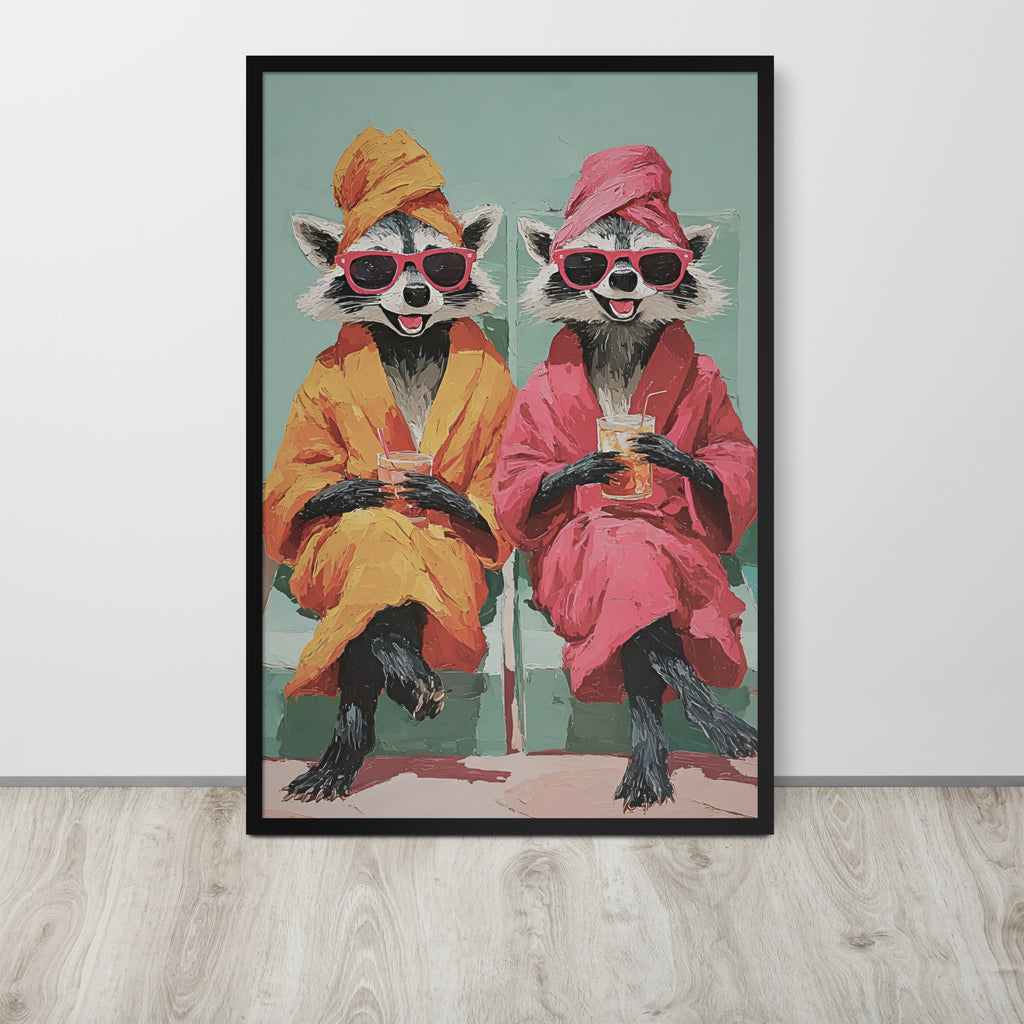 Funny raccoon wall art print featuring two cartoon raccoons wearing pink sunglasses and robes, sitting and holding drinks. The print is displayed on a light gray wall above a light wood floor.
