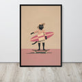 Black cat wall art print leaning against a white wall on a light wood floor. The print shows a black cat wearing a straw hat and sunglasses, holding a pink surfboard while standing on a skateboard against a beige and dusty pink background.