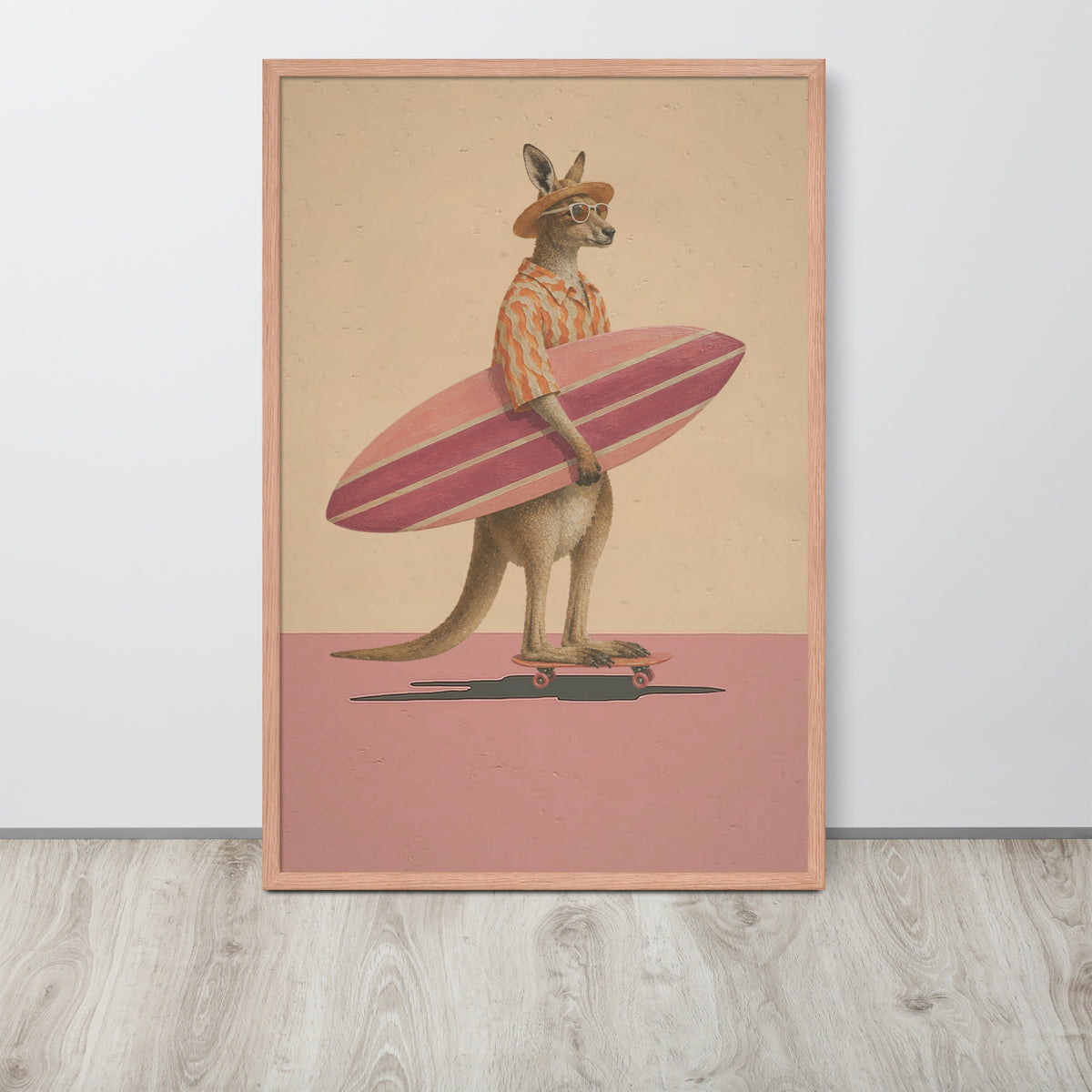 A framed wall art print featuring an anthropomorphic kangaroo wearing a striped shirt and hat, holding a pink surfboard while standing on a skateboard. The print is displayed leaning against a white wall on a light wood floor.
