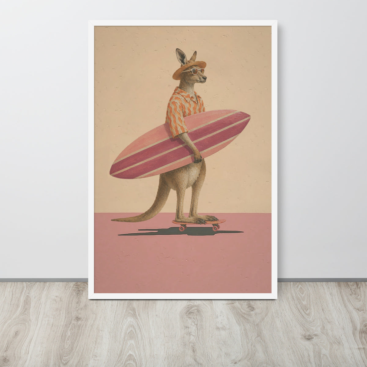 A framed vertical funny animal art print leaning against a light gray wall on a wood floor. The artwork shows a kangaroo standing on a skateboard and holding a pink striped surfboard, with a beige background and pink ground.