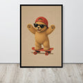 A framed teddy bear nursery wall art print featuring a cute cartoon teddy bear wearing a red cap and black sunglasses while riding a red skateboard, displayed against a light gray wall on a light wood floor.