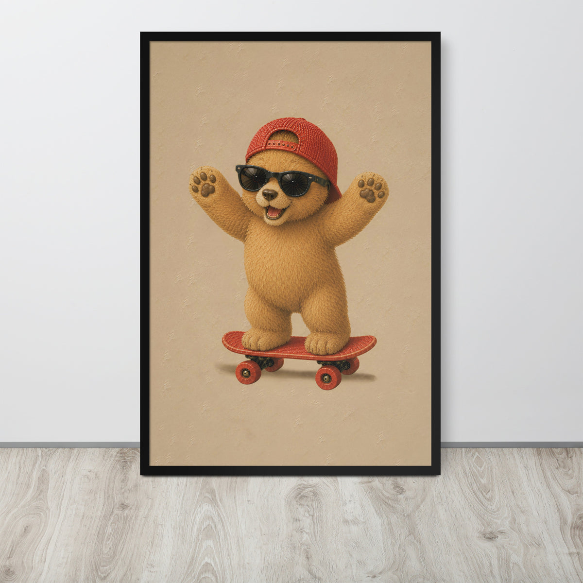 A framed teddy bear nursery wall art print featuring a cute cartoon teddy bear wearing a red cap and black sunglasses while riding a red skateboard, displayed against a light gray wall on a light wood floor.