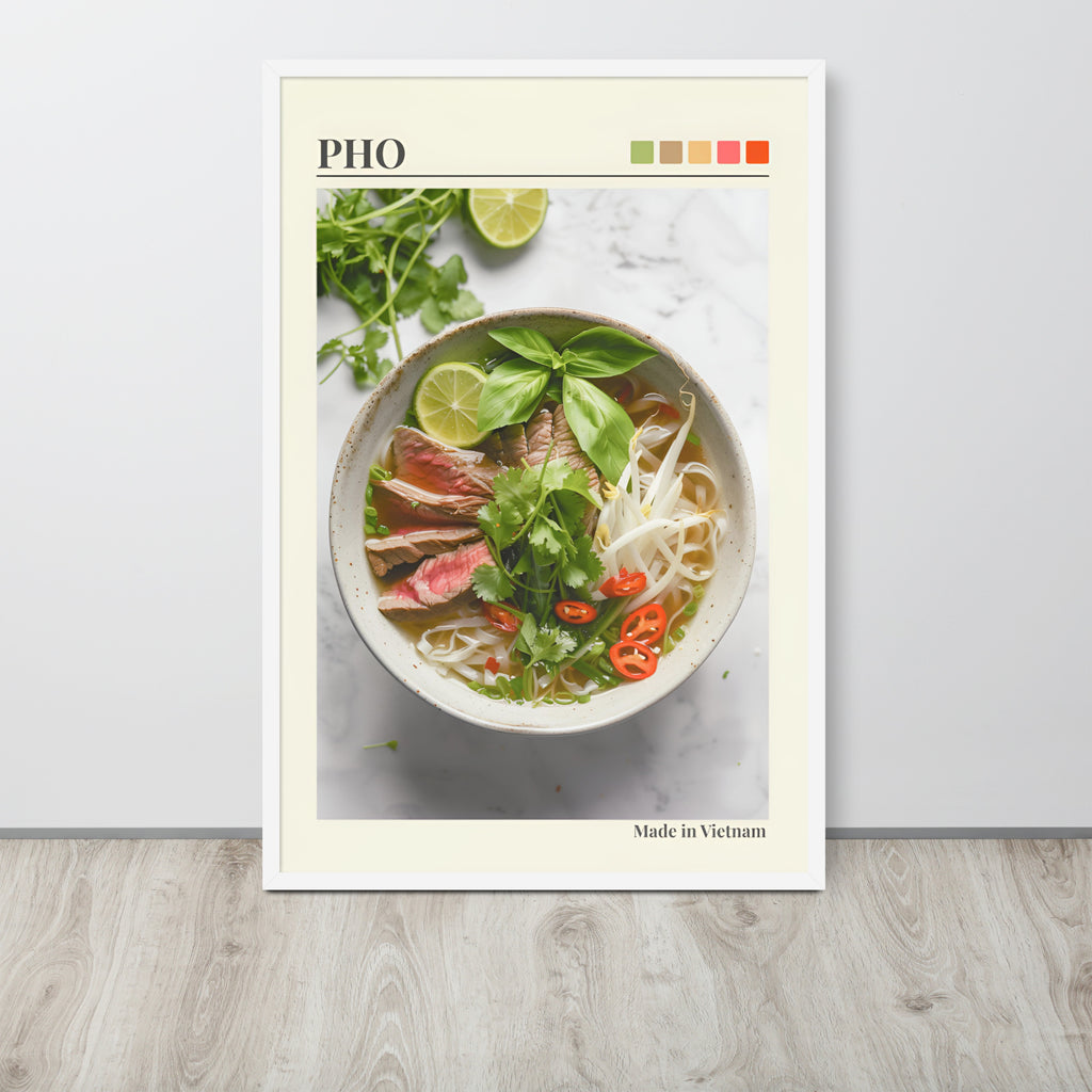 Vietnamese pho wall art print leaning against a light wall on a wood floor. The print features a photograph of a bowl of pho noodle soup with basil, lime, and red chilli, with the word 'PHO' at the top and 'Made in Vietnam' at the bottom.