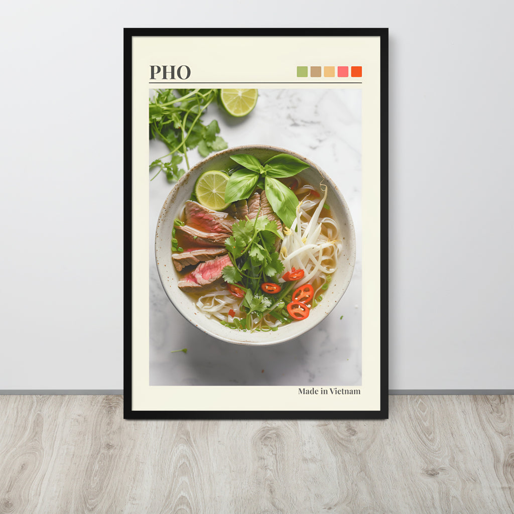 Pho Lover Decor art print featuring a bowl of pho noodle soup with basil, lime, and red chilli, displayed against a light wall on a wood floor. The print has a cream border, the word 'PHO' at the top, a small colour palette, and 'Made in Vietnam' at the bottom.
